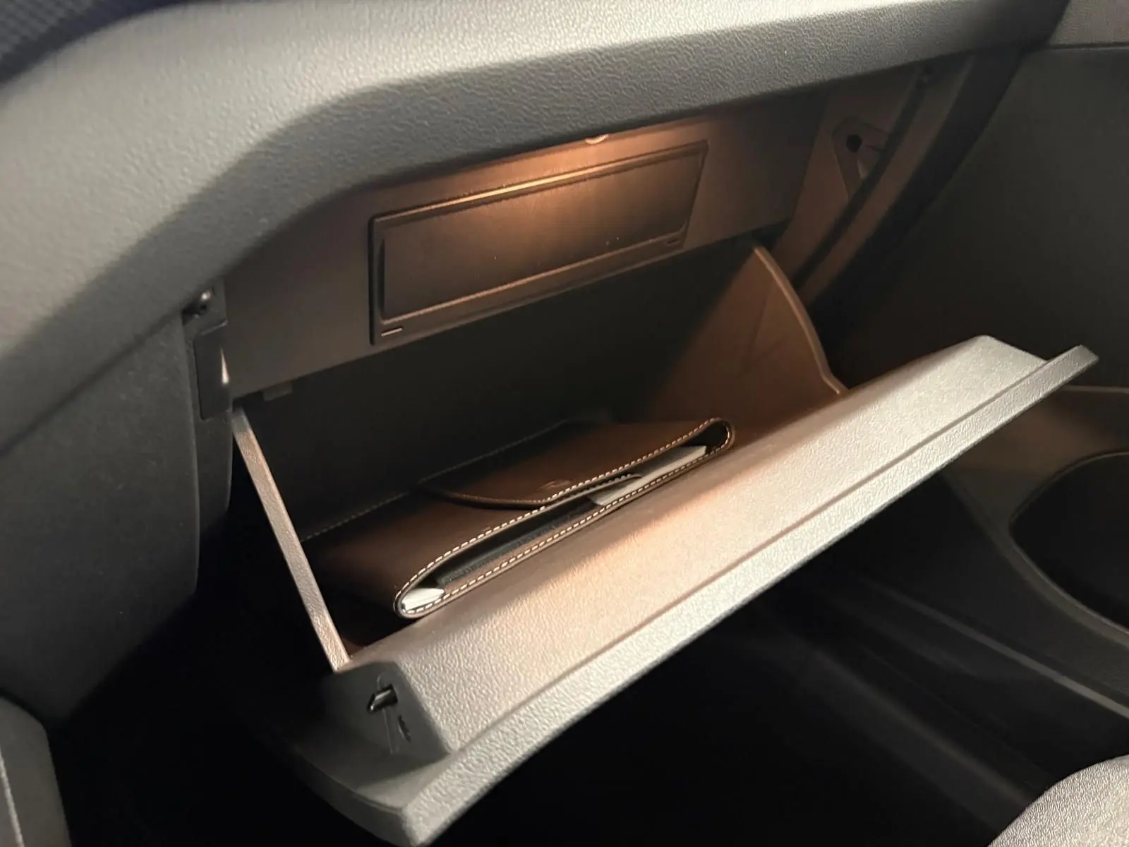 Gant de boîte à gants ouvert dans l'habitacle noir du Volkswagen T-Cross 2024, version Life Plus.