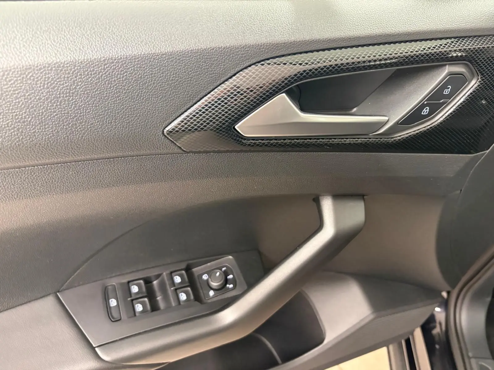Poignée de porte côté gauche du Volkswagen T-Cross noir intense 2024 avec commandes de vitres et verrouillage.