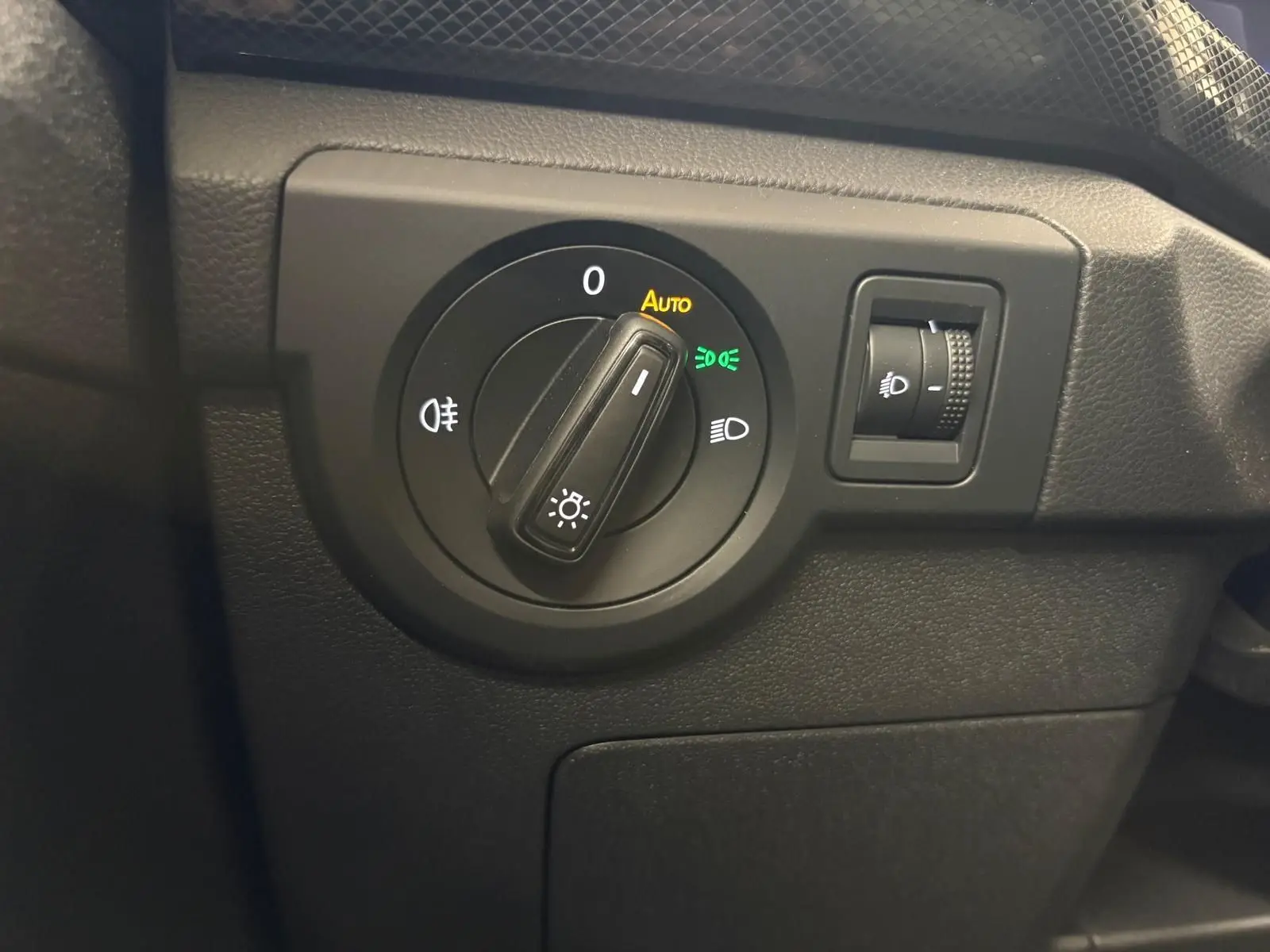 Gros plan sur le sélecteur d'éclairage noir du tableau de bord du Volkswagen T-Cross 2024 finition Life Plus.