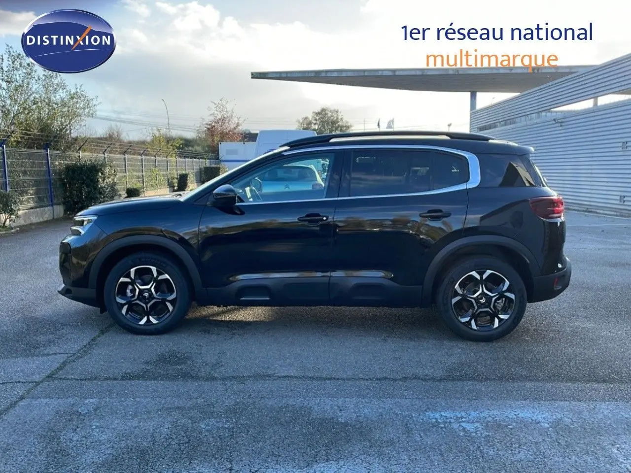 Profil côté gauche d'un Citroën C5 Aircross noir perla metal avec jantes distinctives, stationné en extérieur.