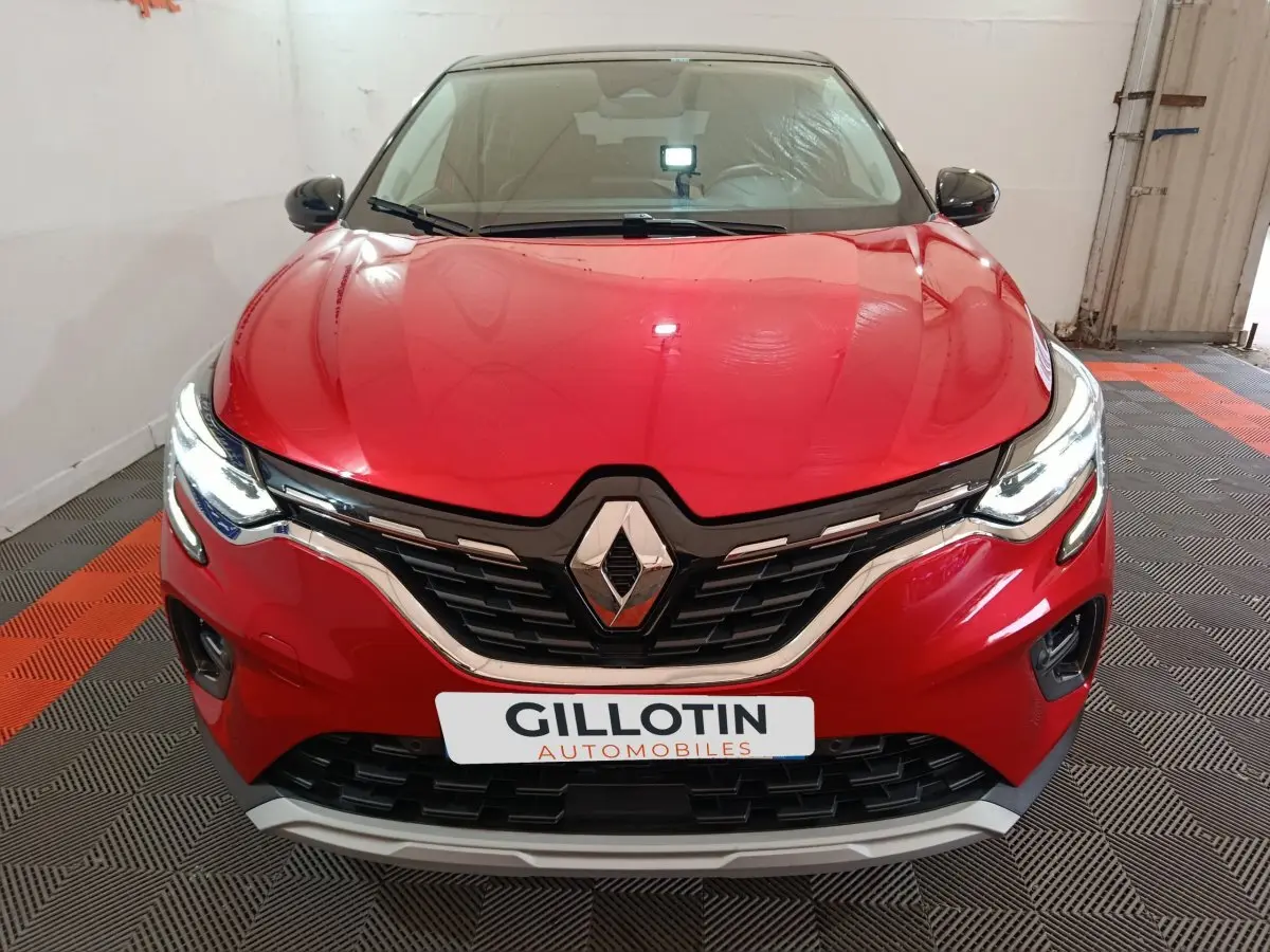 Vue frontale d'un Renault Captur Techno TCe 90 rouge 2024 avec feux LED allumés et calandre noire chromée.