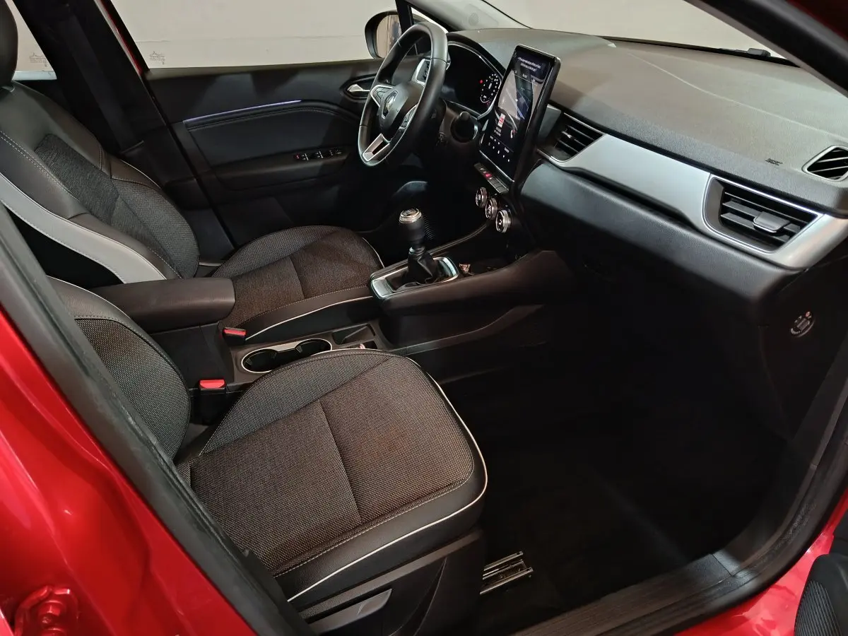 Intérieur Renault Captur 2024 rouge, vue côté conducteur, volant multifonctions et écran tactile vertical.
