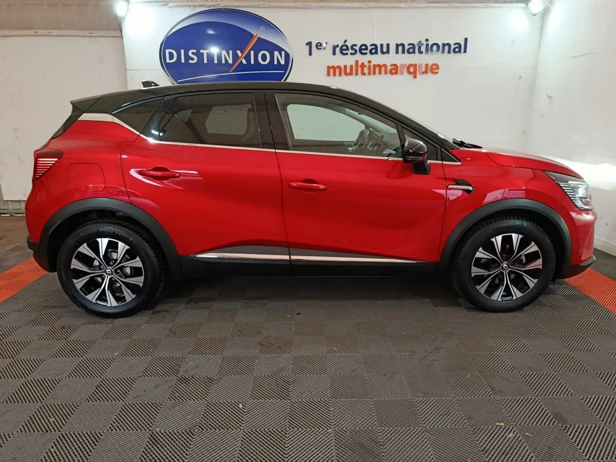 Profil latéral droit d'un Renault Captur rouge 2024 avec toit noir et jantes alliage bicolores.