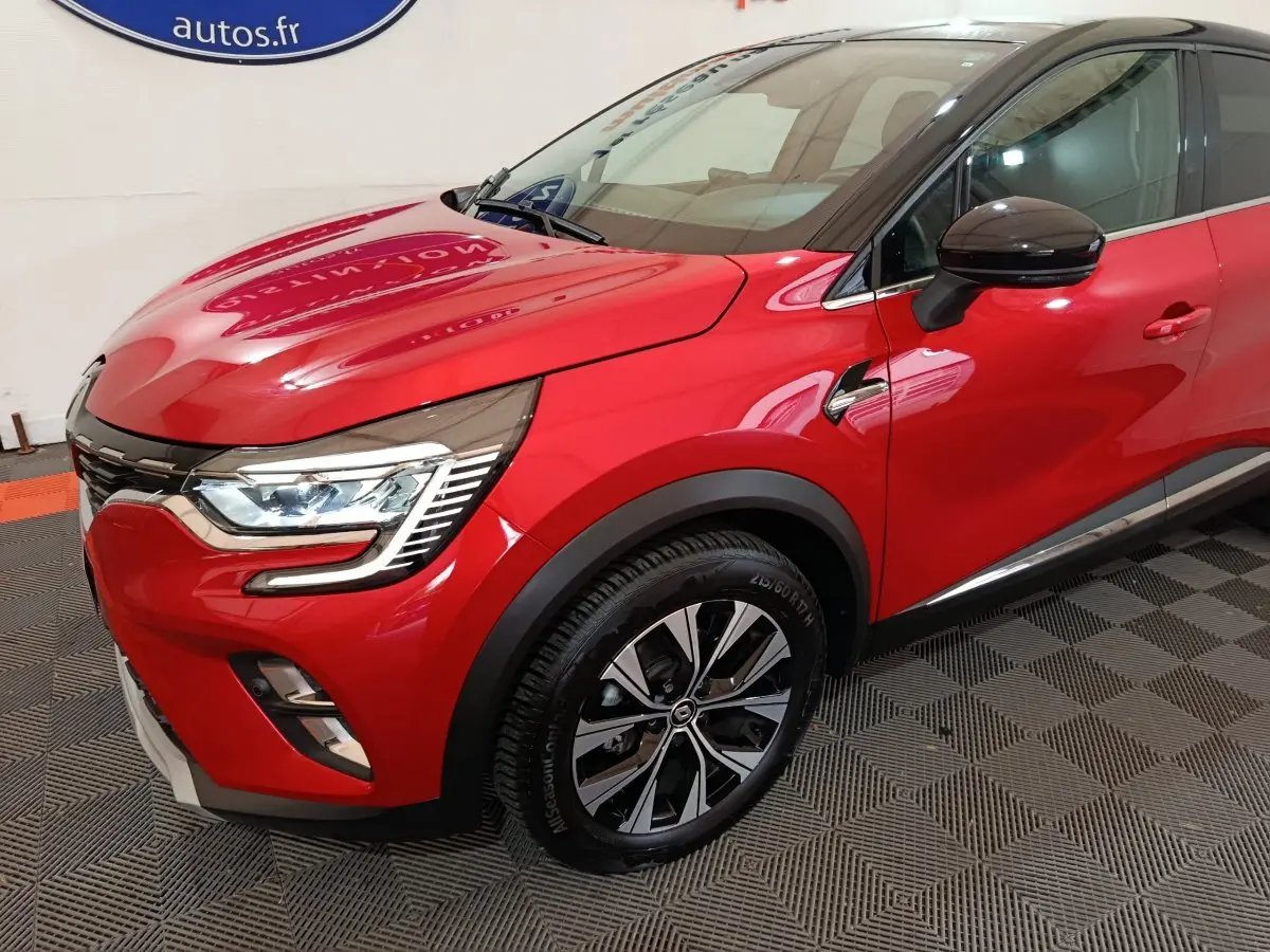 Vue 3/4 avant droit du Renault Captur Techno TCe 90 rouge avec toit noir et jantes alliage distinctives.