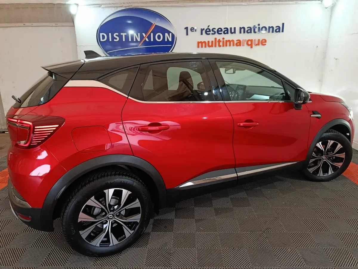 Vue latérale droite d’un Renault Captur Techno TCe 90 rouge 2024 avec toit noir et jantes alliage bicolores.