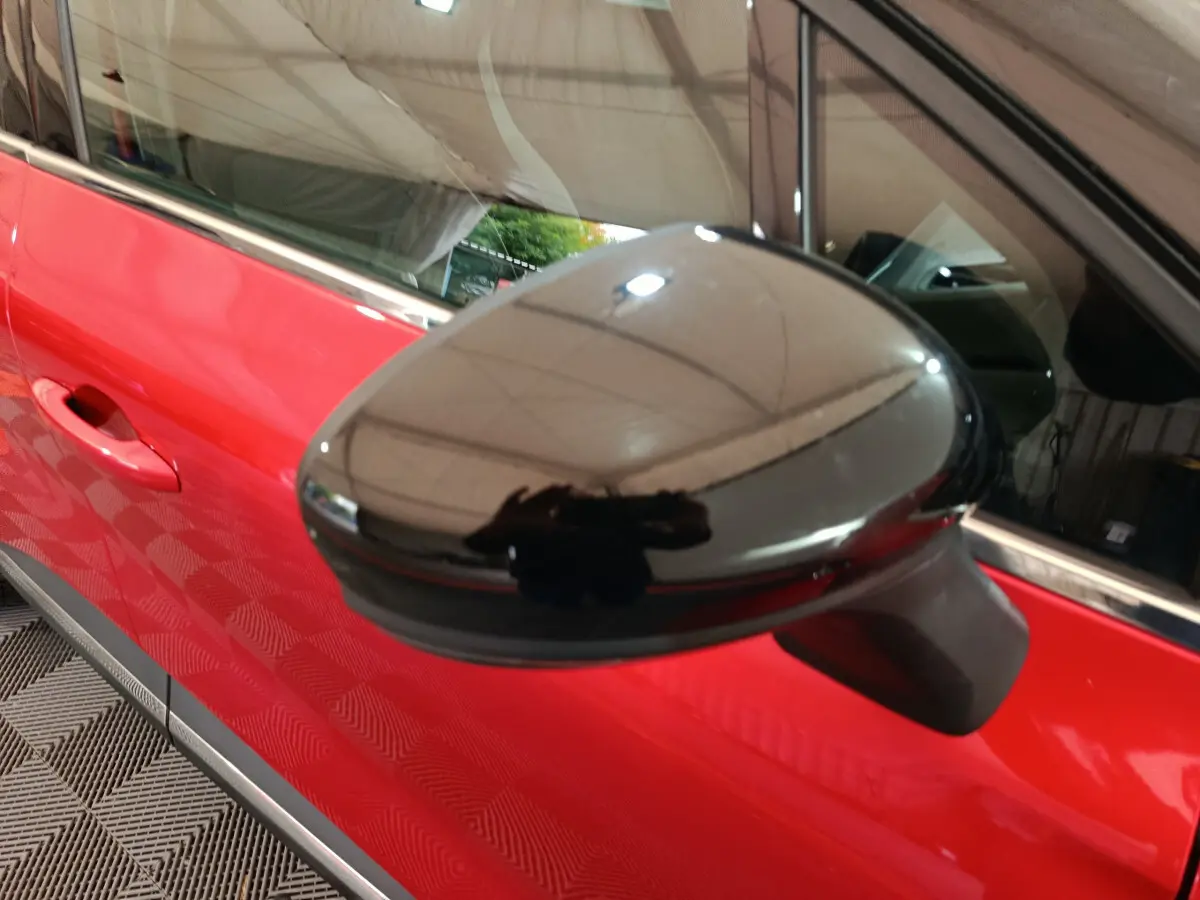 Rétroviseur extérieur noir en gros plan sur le côté gauche d’un Renault Captur rouge 2024, vue rapprochée.
