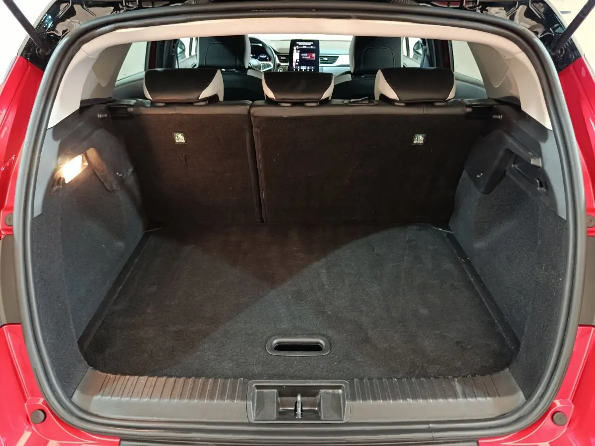 Coffre ouvert d’un Renault Captur rouge 2024, vue arrière montrant l’espace de chargement et les sièges arrière rabattables.