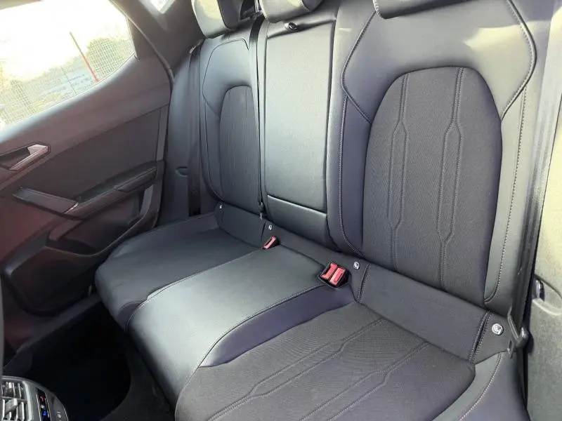 Vue intérieure des sièges arrière noirs du SEAT LEON 2025, avec ceintures de sécurité et accoudoir central rabattable.