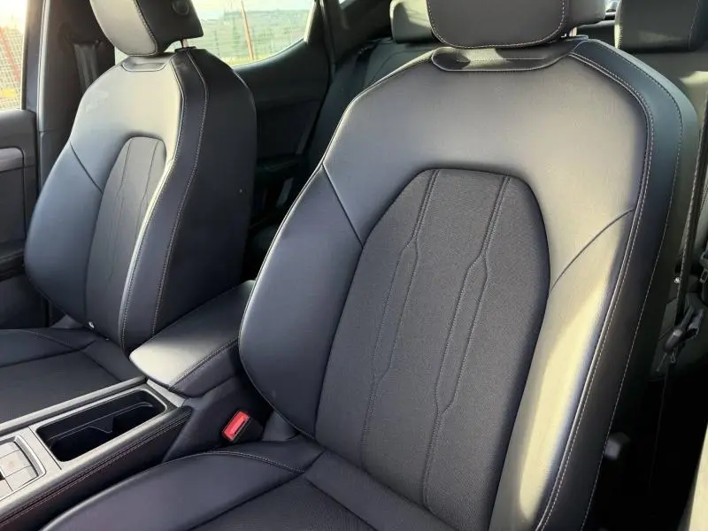 Vue rapprochée des sièges avant en cuir noir avec surpiqûres blanches du SEAT LEON 1.5 eTSI Hybrid 2025.