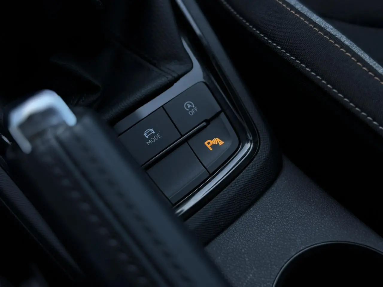 Gros plan sur les boutons de contrôle du mode de conduite et du radar de stationnement orange, intérieur noir de la Skoda Scala.