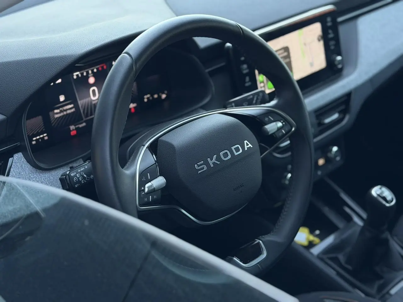 Vue intérieure centrée sur le volant cuir multifonctions SKODA et la console avec levier de vitesses manuel de la Scala 2025.