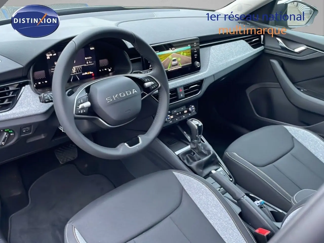 Vue intérieure côté conducteur du Skoda Kamiq 2025, montrant le volant, tableau de bord numérique et sellerie tissu gris et noir.