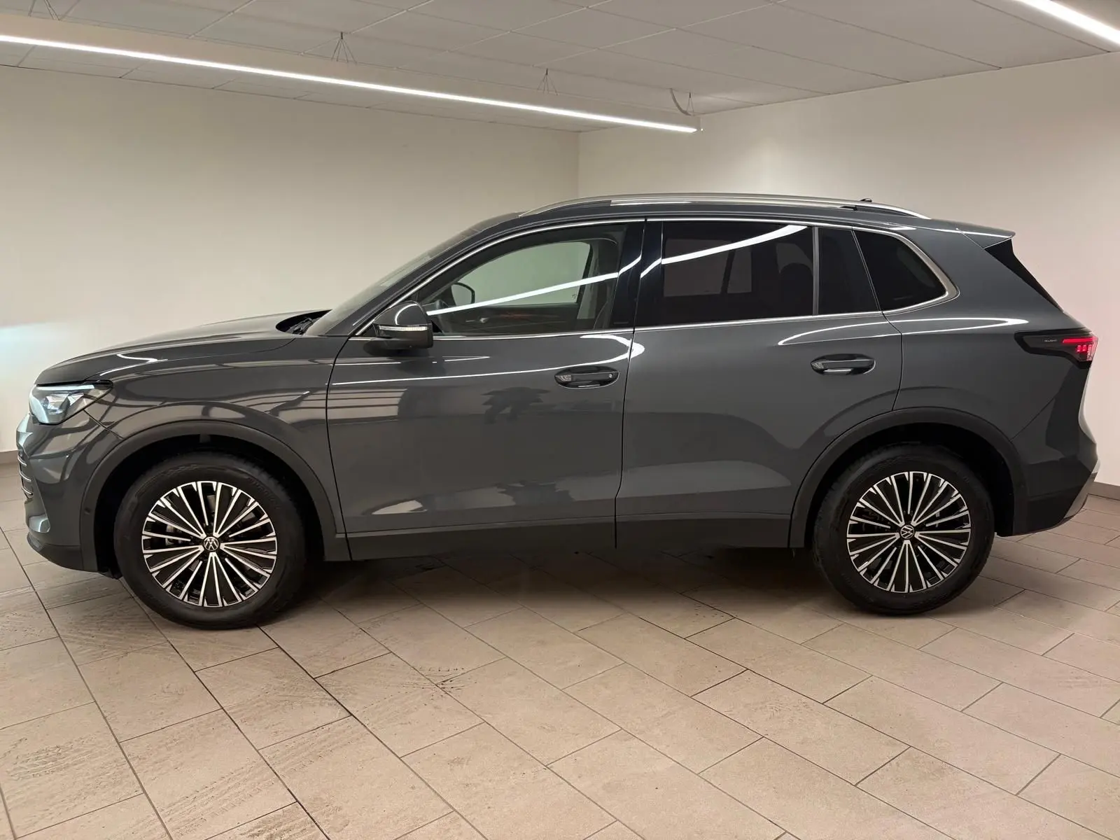 Vue de profil côté gauche du Volkswagen Tiguan 2.0 TDI 150 DSG7 Elegance 2025 en gris dauphin métallisé, roues alliage distinctives.