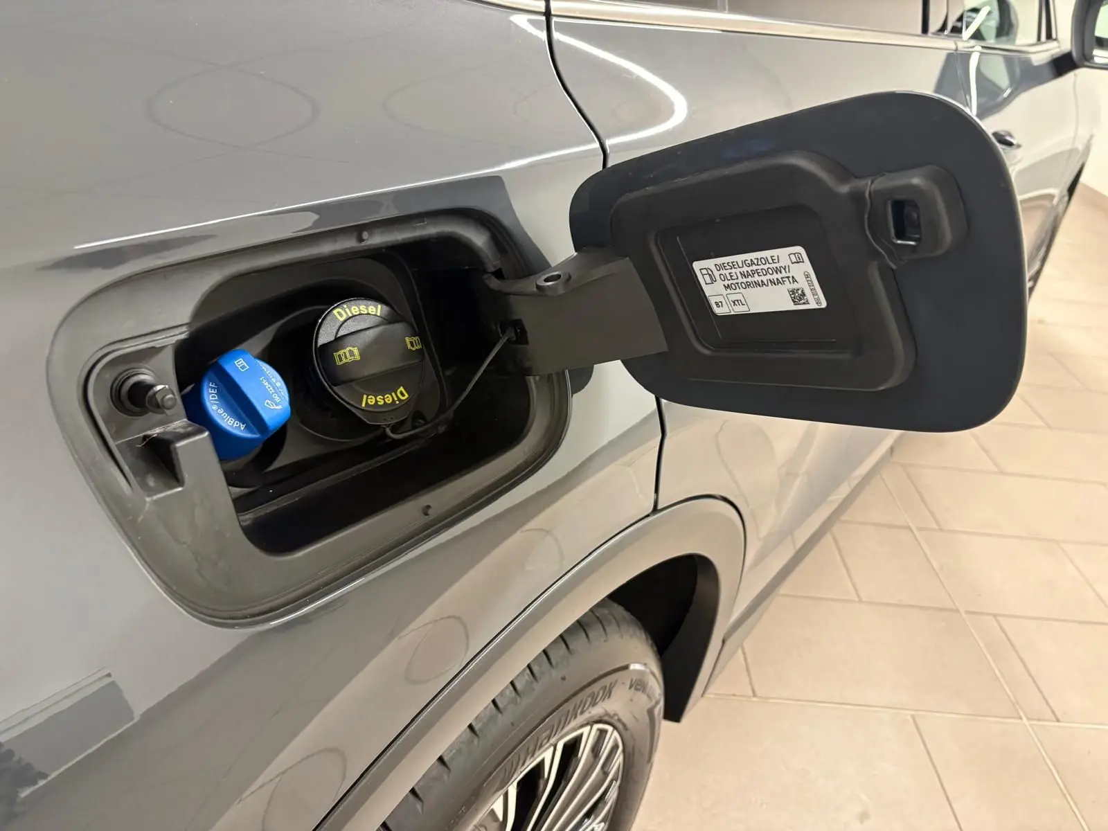 Gros plan sur la trappe à carburant côté gauche d'un Volkswagen Tiguan gris Dauphin, avec bouchons diesel et AdBlue visibles.
