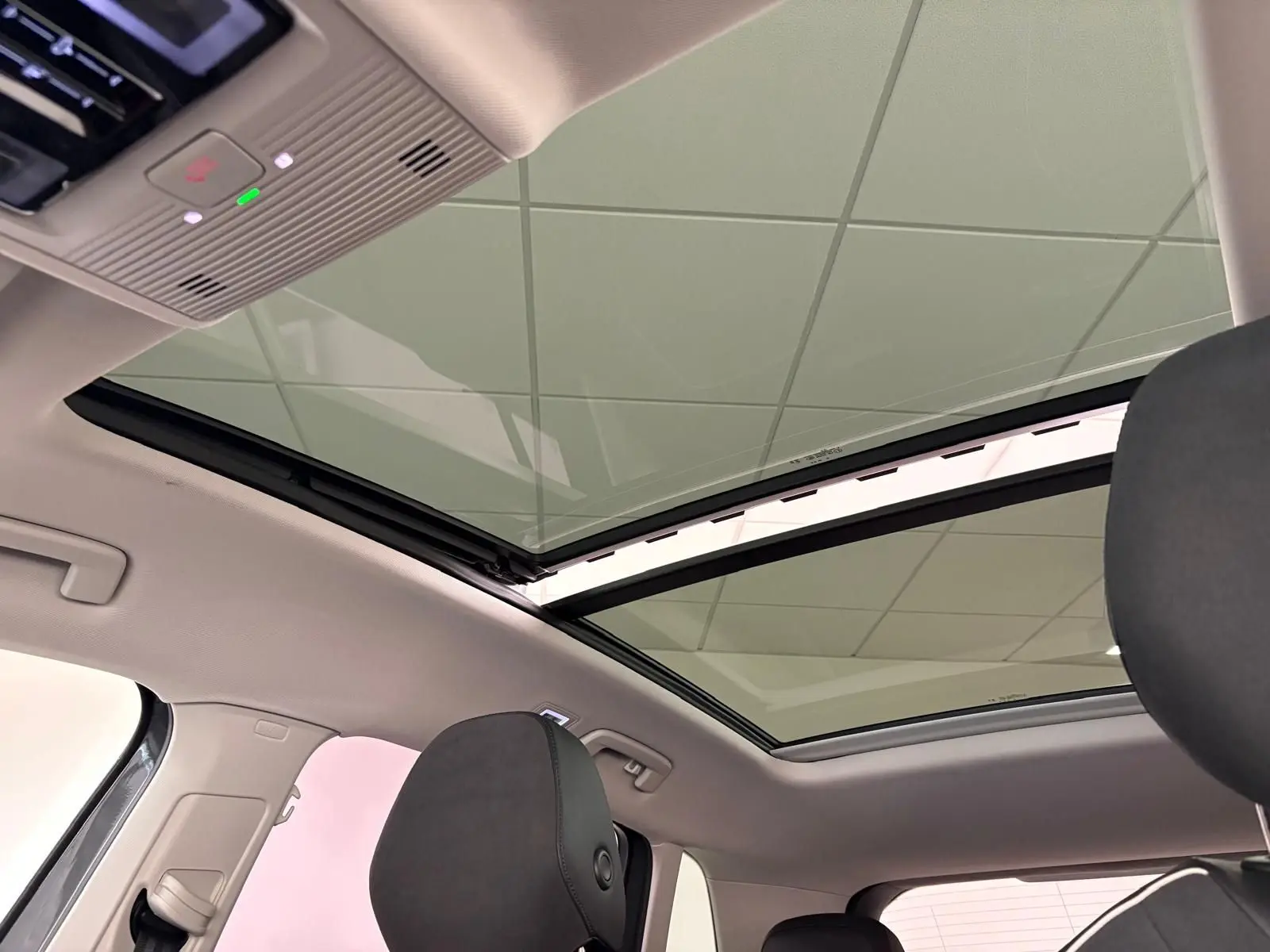 Toit panoramique ouvert vu de l'intérieur arrière du Volkswagen Tiguan gris Dauphin avec ciel de toit clair.