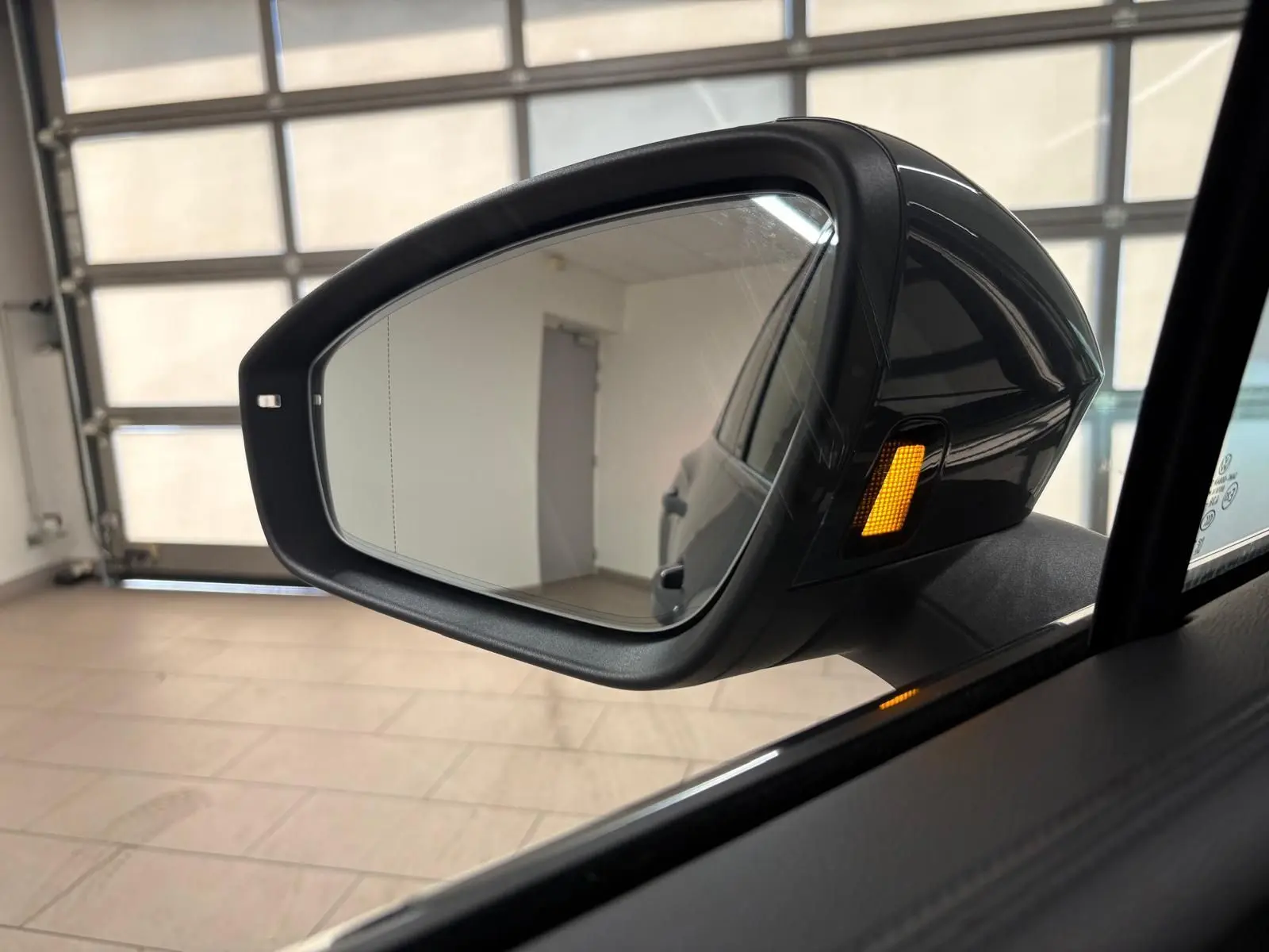 Rétroviseur extérieur droit du Volkswagen Tiguan 2.0 TDI 150 DSG7 Elegance gris Dauphin avec clignotant orange allumé.