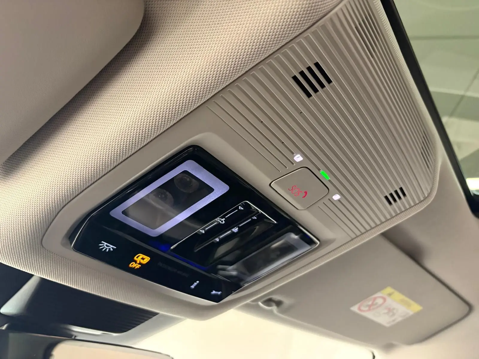 Vue en gros plan du plafonnier intérieur beige avec commandes d’éclairage et bouton SOS du Volkswagen Tiguan 2025.