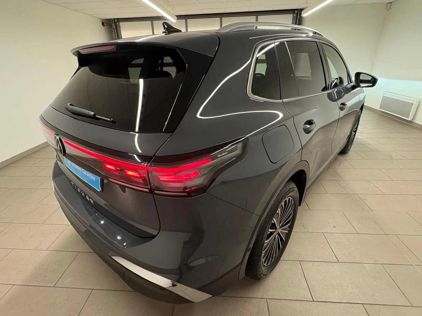 Vue 3/4 arrière droit du Volkswagen Tiguan 2.0 TDI 150 DSG7 Elegance gris dauphin métallisé avec feux arrière allumés.