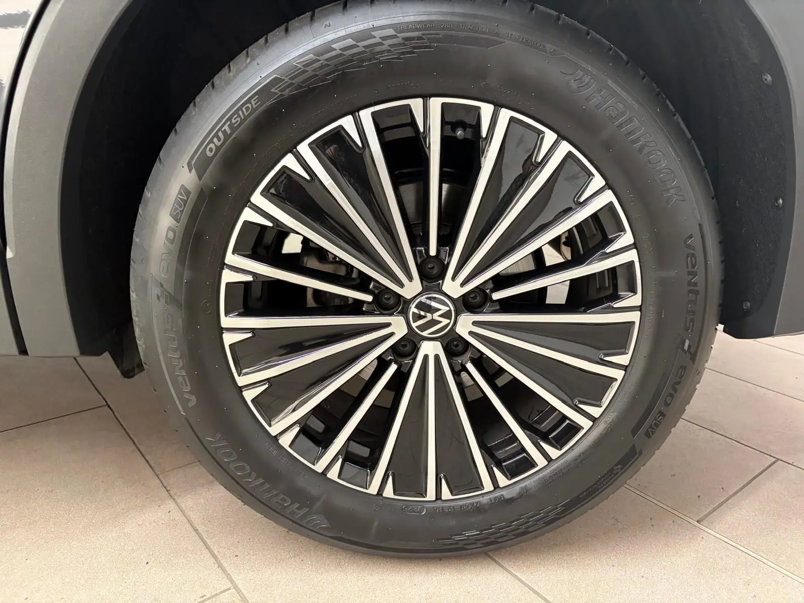 Gros plan sur la jante avant droite du Volkswagen Tiguan 2.0 TDI 150 DSG7 Elegance gris Dauphin avec logo VW central.