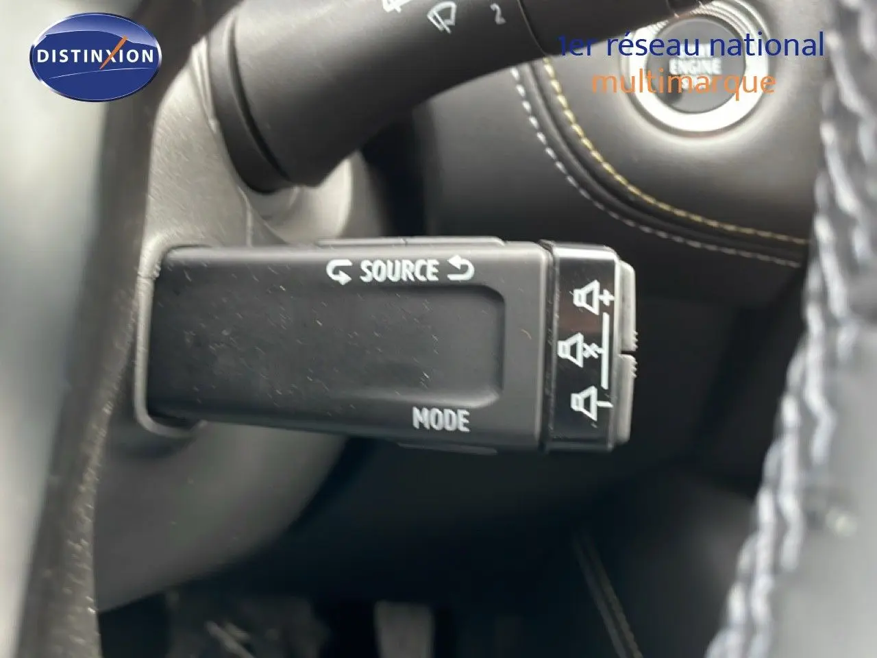 Gros plan sur la commande multimédia au volant du Renault Symbioz bleu iron metal, avec bouton source et mode visibles.