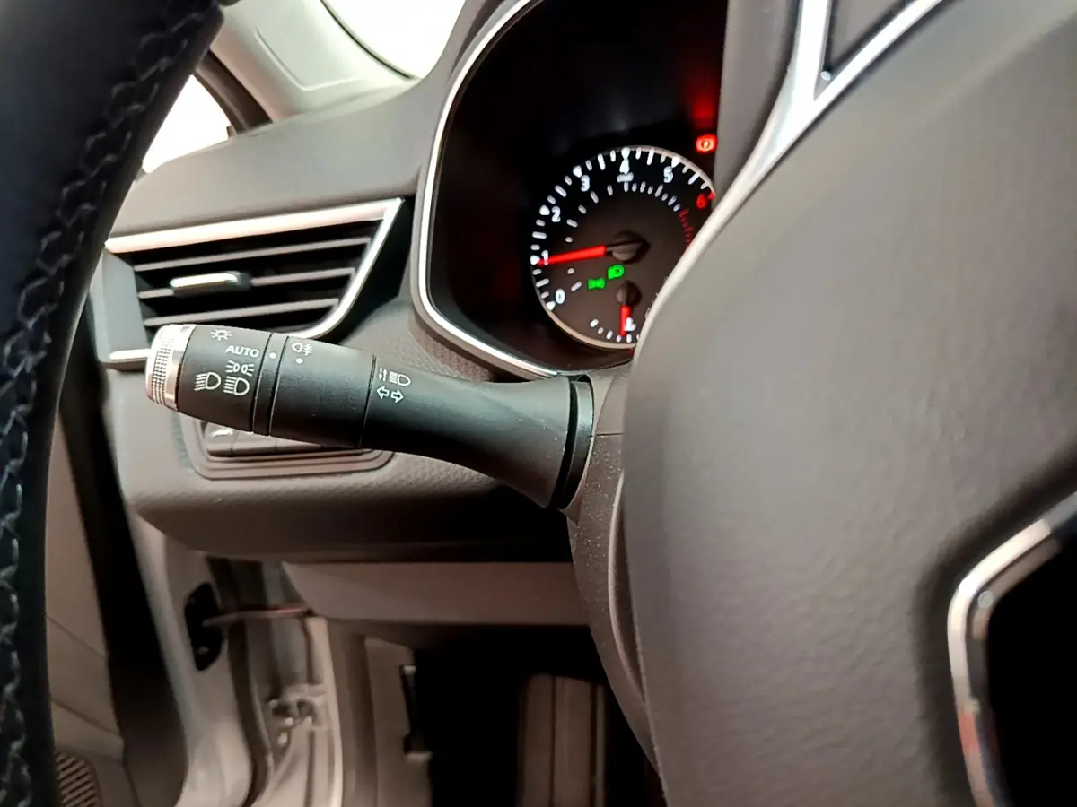 Gros plan sur le commodo d’éclairage à gauche du volant dans l’habitacle gris clair de la Renault Clio Business TCe 100 2020.