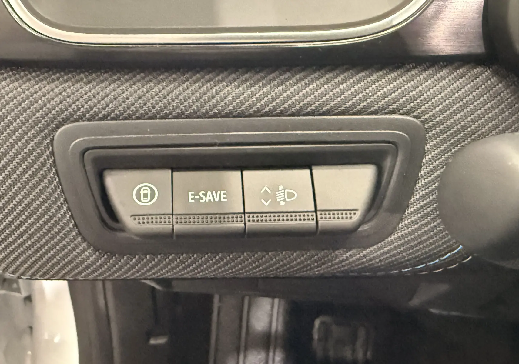 Gros plan sur les boutons de commande E-SAVE et réglage des phares dans l’habitacle du Renault Captur blanc nacré toit noir.