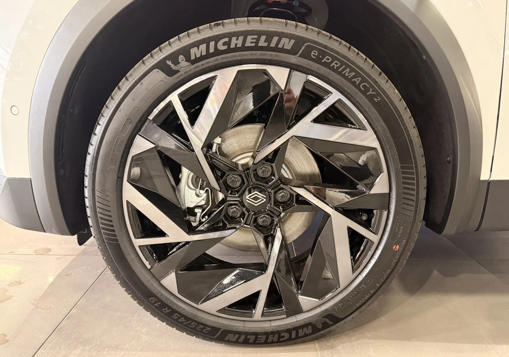 Gros plan sur la jante avant droite du Renault Captur E-Tech blanc nacré, avec un design noir et argenté et pneu Michelin.