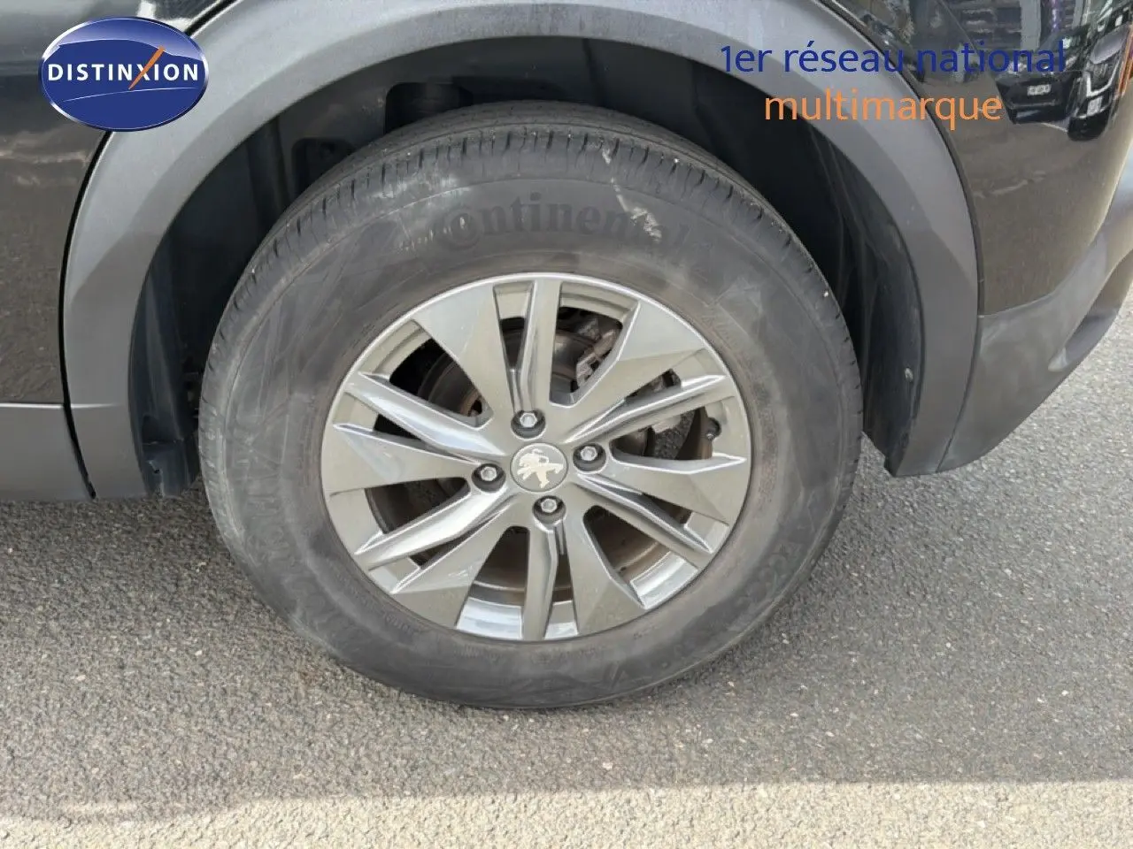 Gros plan sur la roue avant gauche du Peugeot 2008 noir perle métal avec jante alliage 16 pouces.