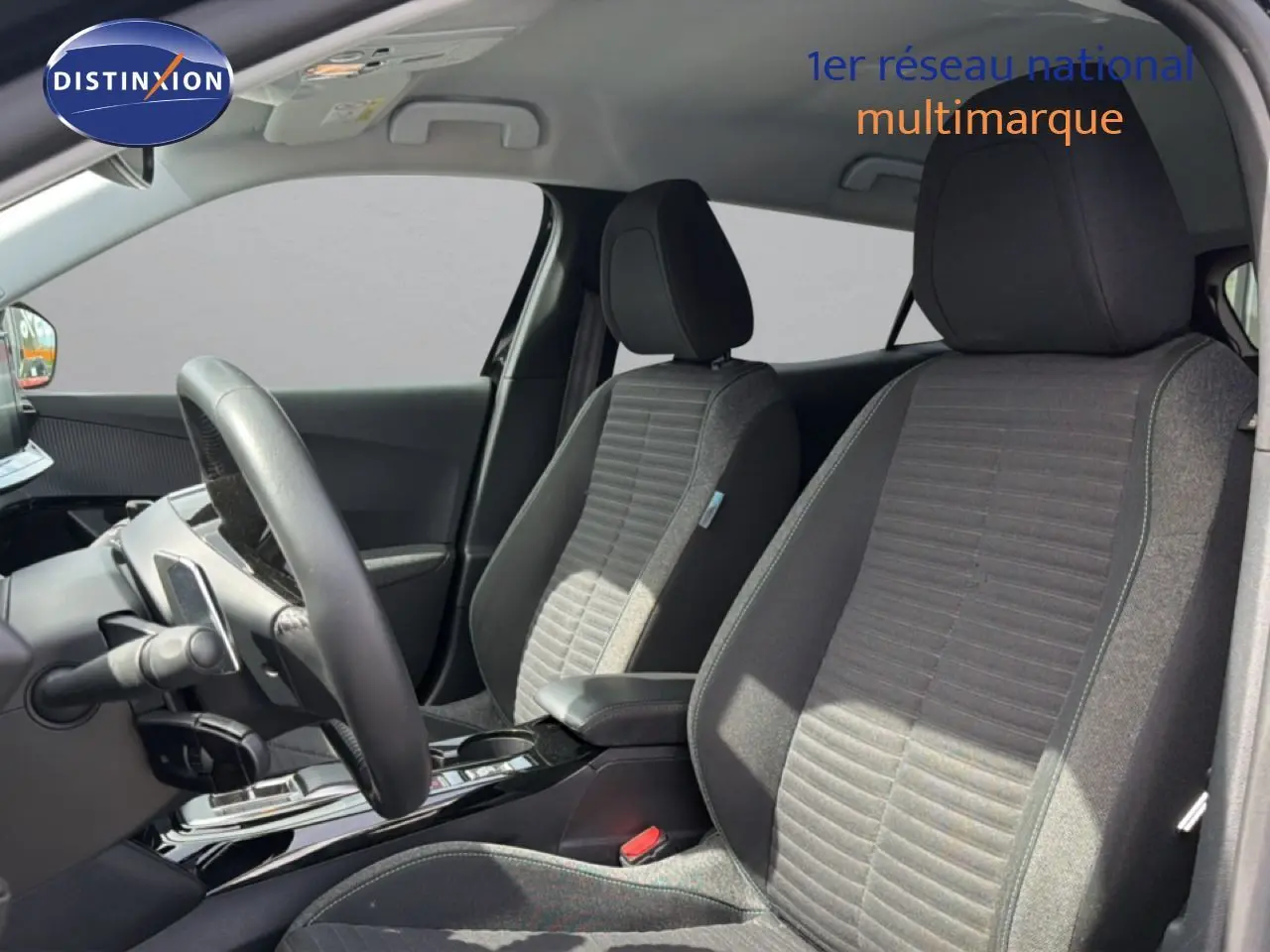 Vue intérieure côté conducteur du Peugeot 2008 2022, sièges tissu noir et console centrale brillante.