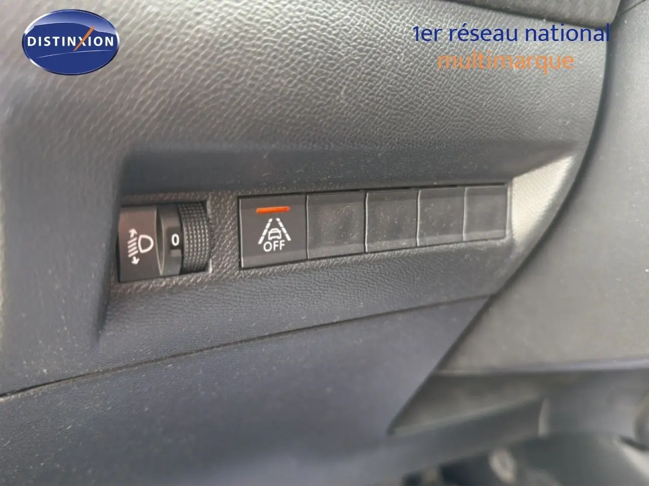 Gros plan sur les commandes de réglage des phares et désactivation de l'alerte de franchissement de ligne dans un Peugeot 2008 noir perle métal.