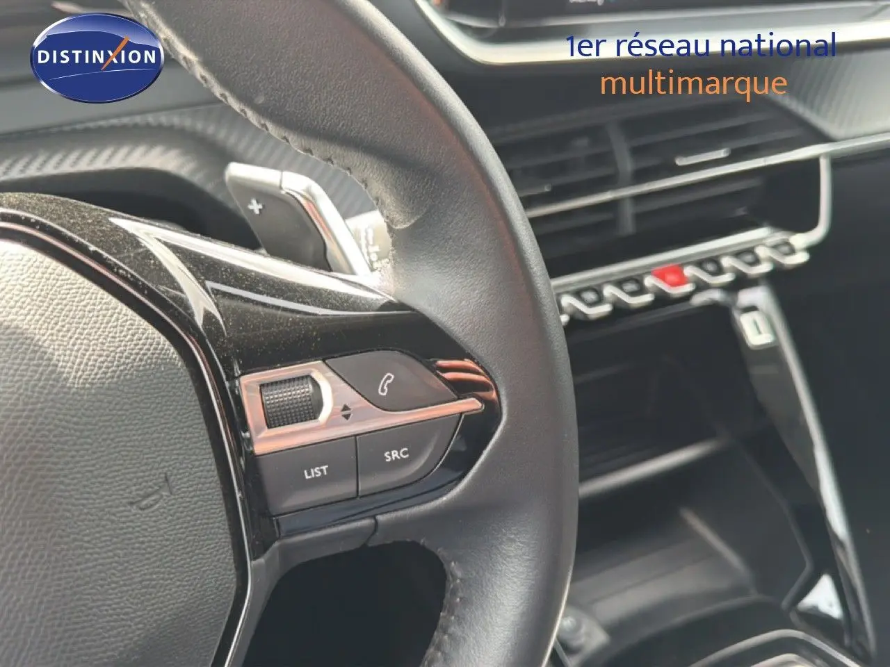 Gros plan sur le volant côté gauche du Peugeot 2008 noir perle métal, avec commandes intégrées et tableau de bord en arrière-plan.