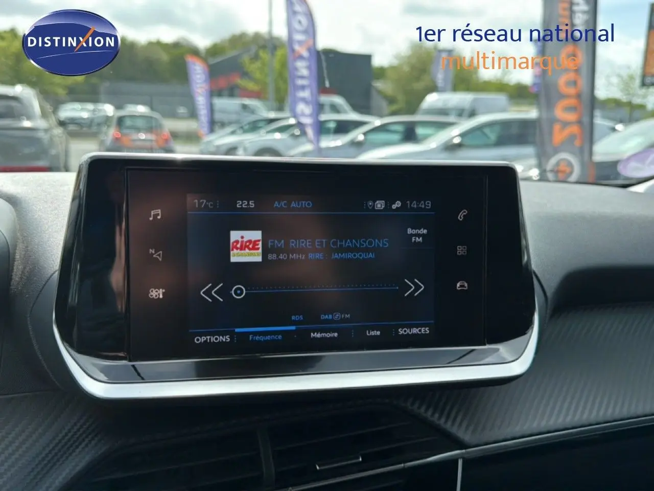 Vue rapprochée de l'écran tactile central du tableau de bord d'une Peugeot 2008 noir perle métal, affichant une radio FM.