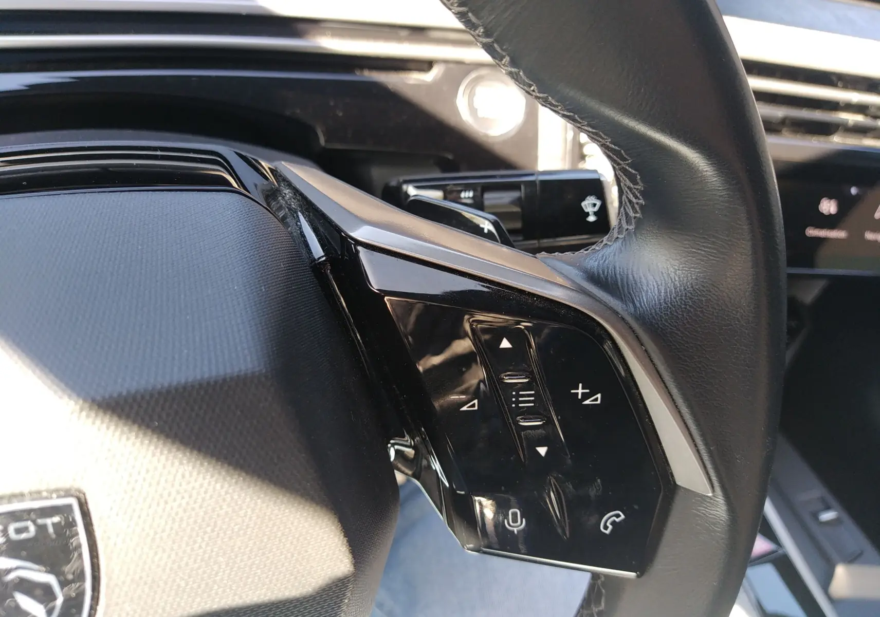 Gros plan sur le volant côté gauche du Peugeot 3008 Hybrid 136 Allure 2024, montrant les commandes intégrées.