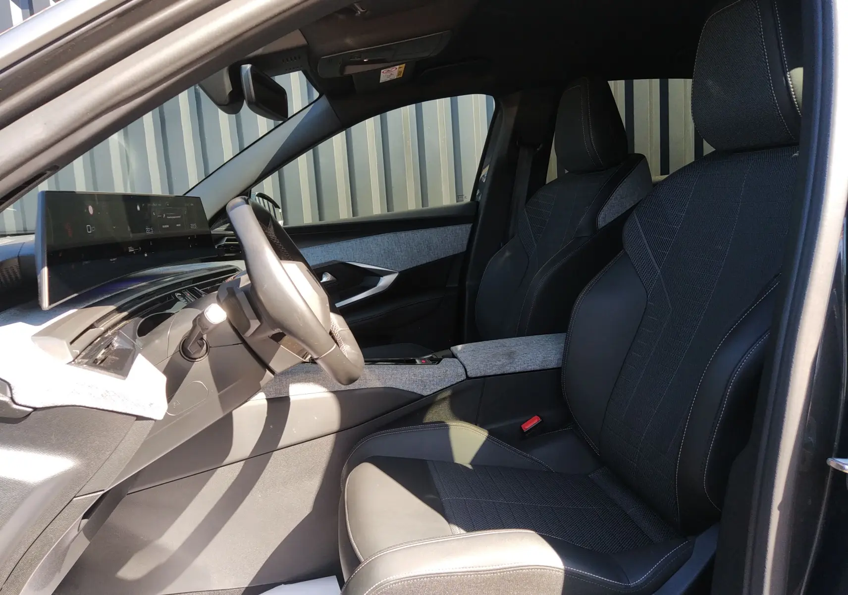 Intérieur avant droit du Peugeot 3008 Hybrid 2024, sièges noirs avec surpiqûres blanches et tableau de bord moderne.