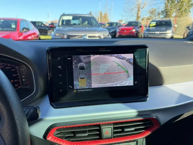 Vue intérieure du tableau de bord de la SEAT Ibiza 2025 avec écran de caméra de recul et détails rouges autour des aérateurs.