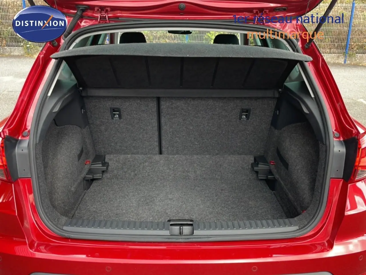 Coffre ouvert vu de l'arrière d'un SEAT Arona rouge désir métal avec toit noir, montrant l'espace de chargement vide.