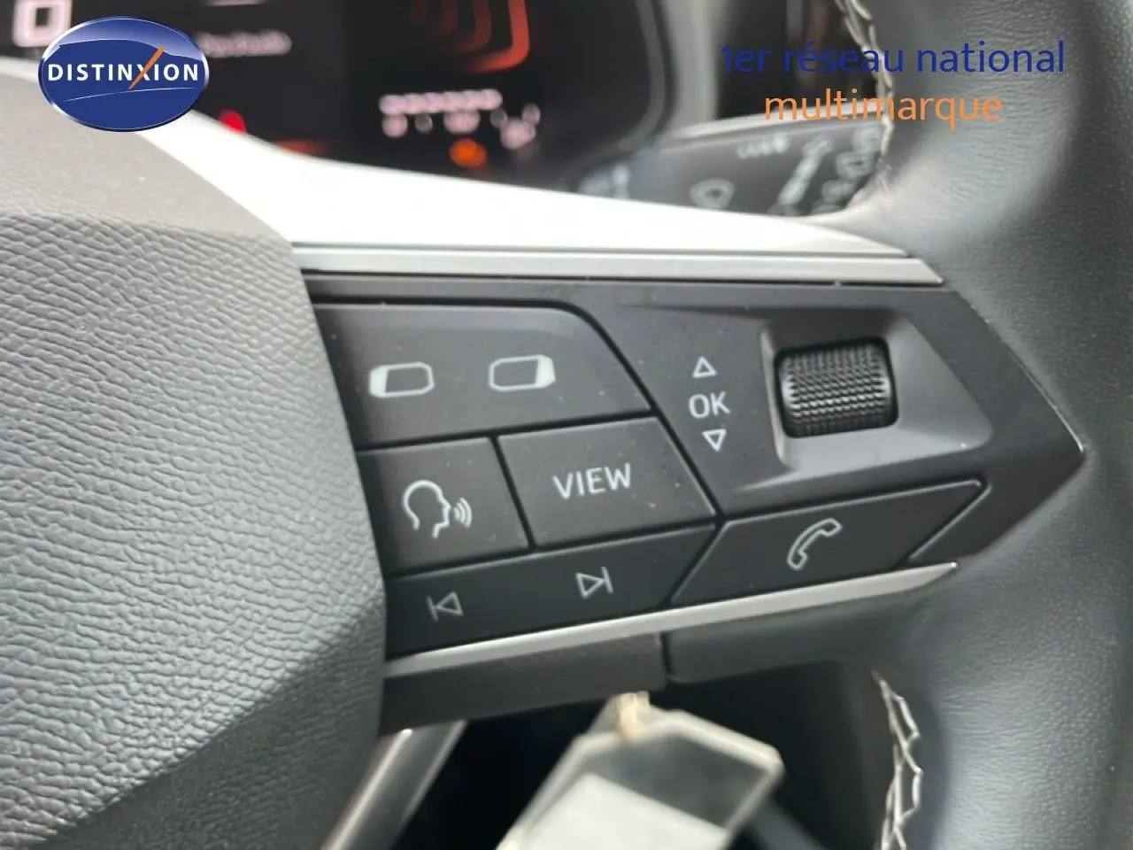 Gros plan sur les commandes multifonctions au volant d’un SEAT Arona rouge Désir Métal avec toit noir, version 2025.