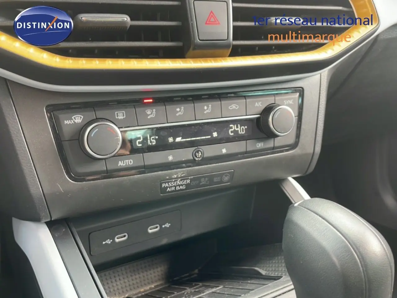 Gros plan sur la console centrale de la SEAT Arona rouge désir métal, montrant la climatisation automatique et le levier de boîte auto.