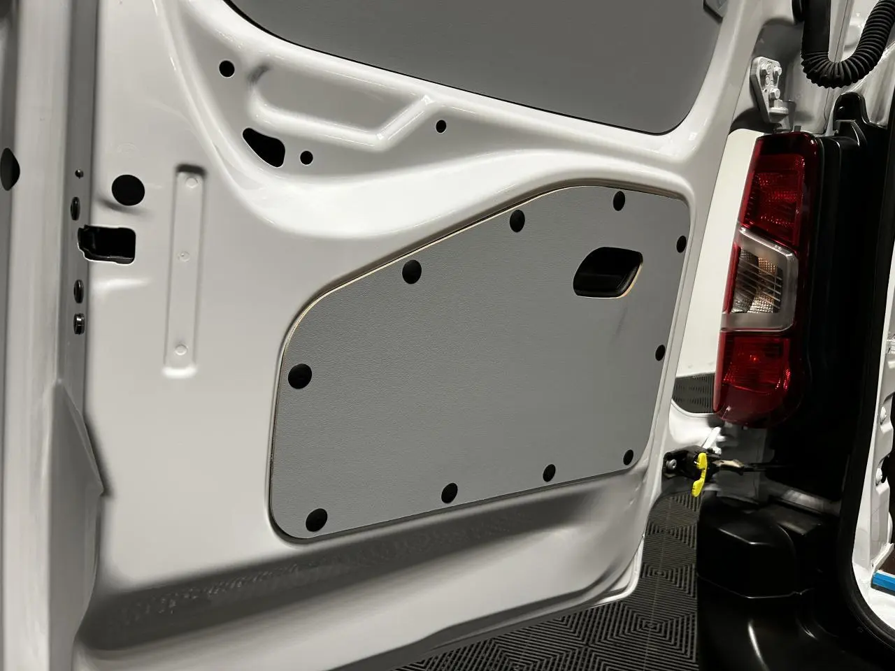 Gros plan sur la porte arrière droite blanche banquise du Peugeot Partner 2025, montrant le panneau intérieur gris et le feu arrière.