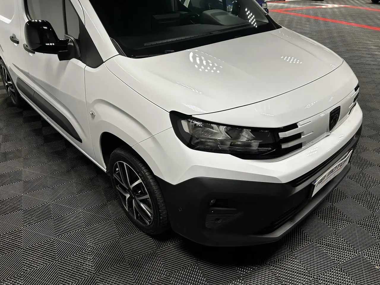 Vue 3/4 avant droit du Peugeot Partner blanc Banquise avec jantes alliage 17 pouces et détails noirs contrastants.