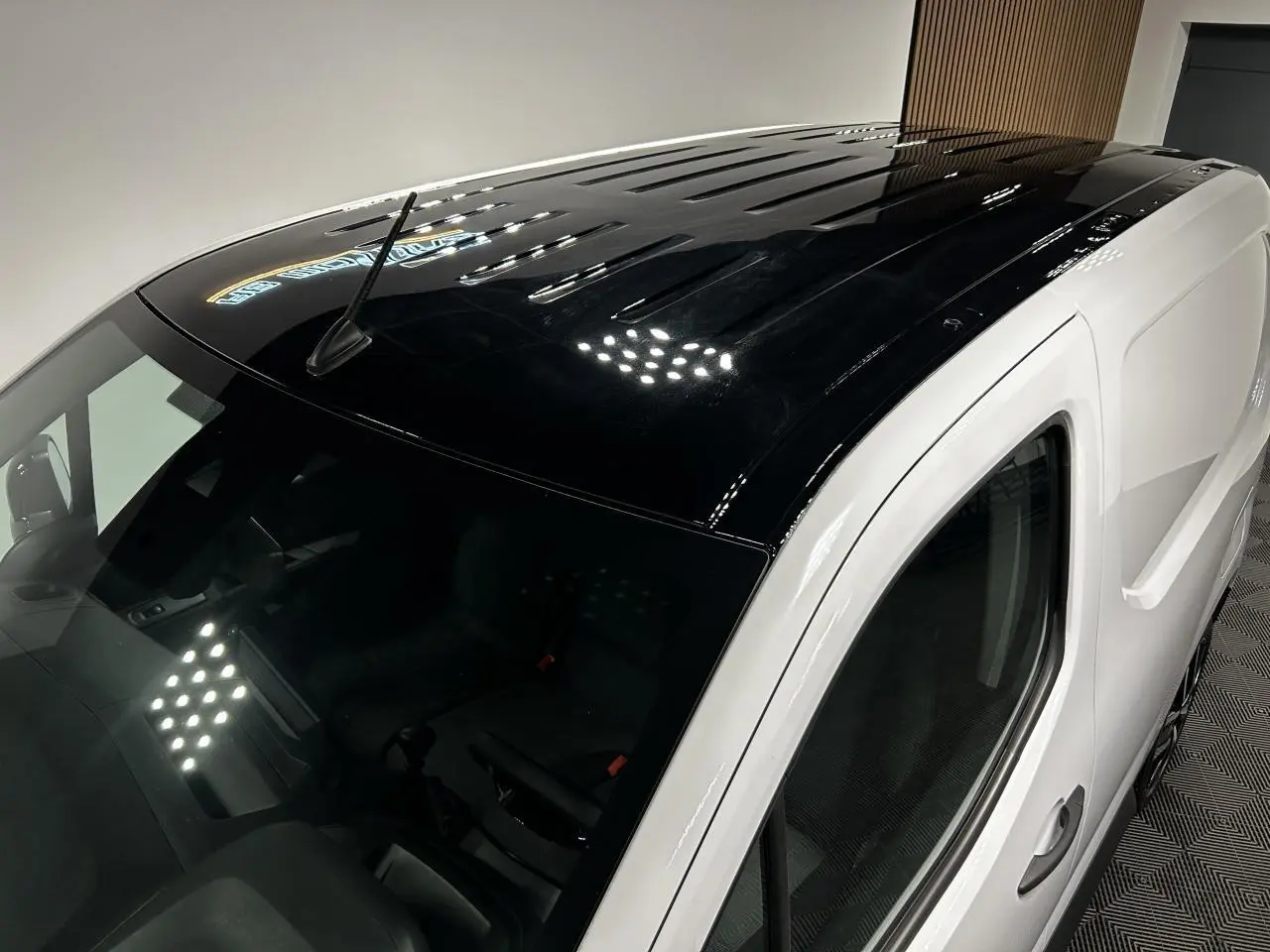 Vue plongeante 3/4 avant droit du Peugeot Partner blanc Banquise avec toit noir brillant et antenne sur le toit.