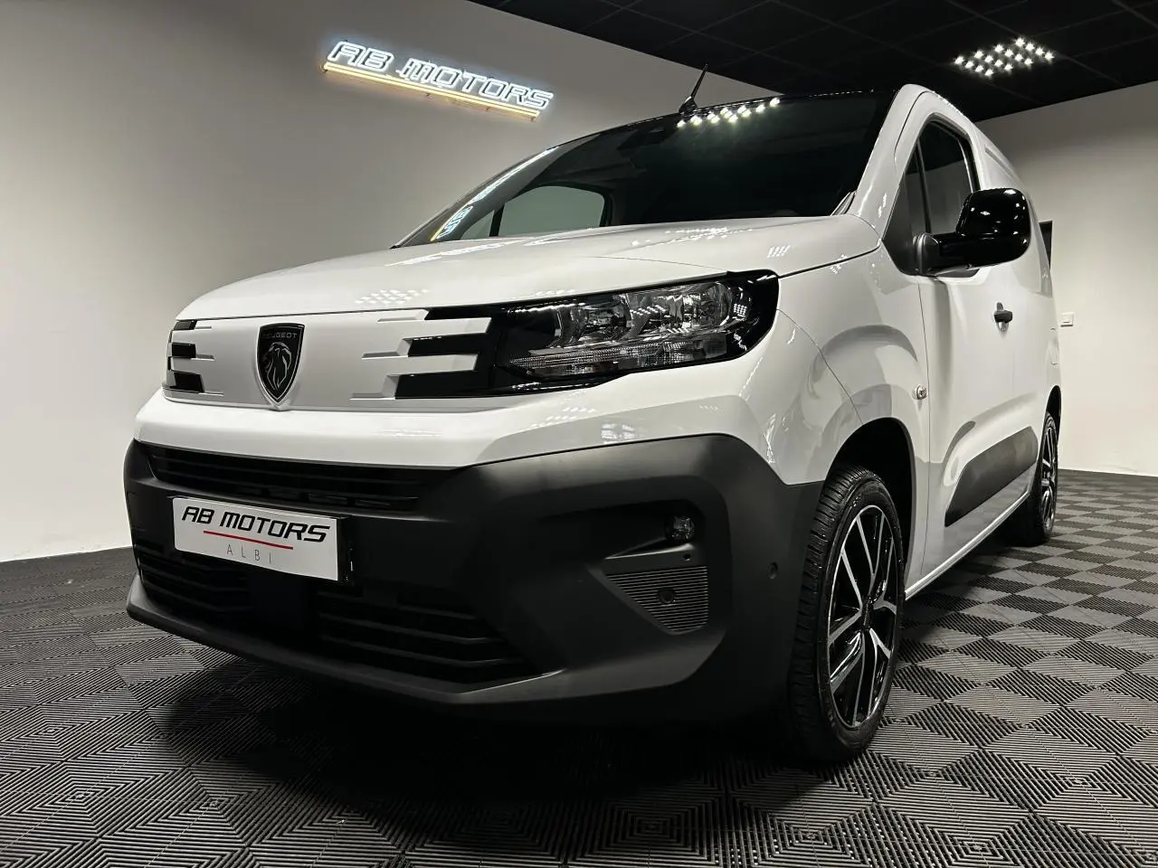 Vue 3/4 avant droit du Peugeot Partner blanc Banquise avec jantes alu 17 pouces et bouclier noir contrasté.