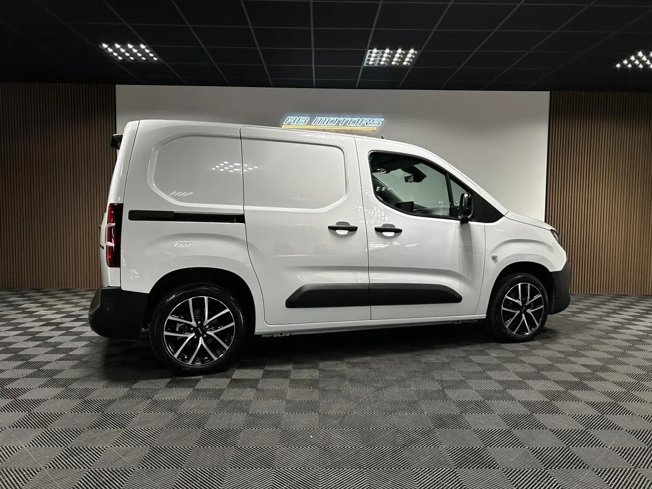 Vue latérale droite du Peugeot Partner blanc Banquise 2025 avec jantes alliage 17 pouces et protections noires.