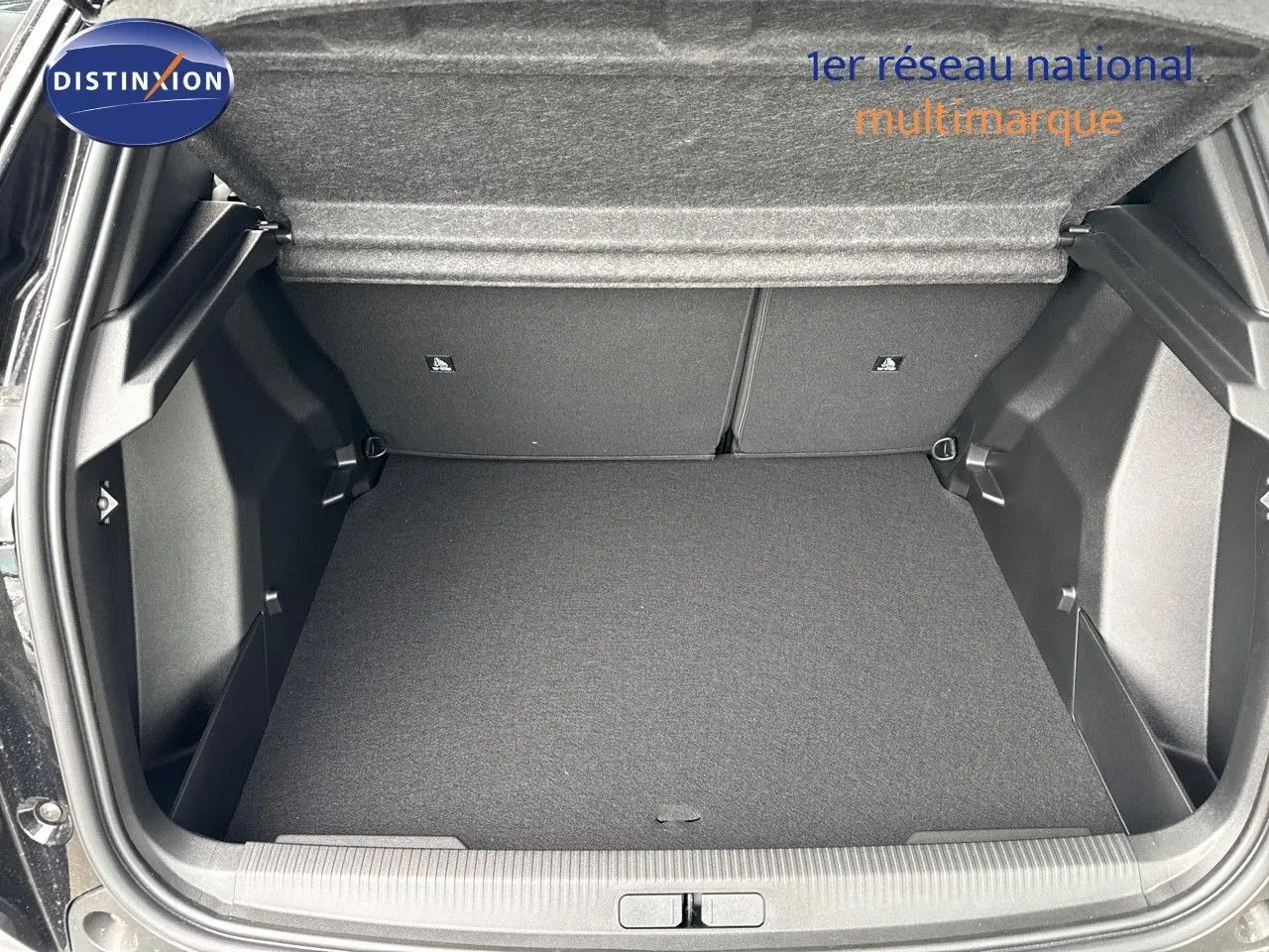Coffre ouvert vu de l'arrière d'un Peugeot 2008 noir métal hybride 2025, espace de chargement vide et propre.