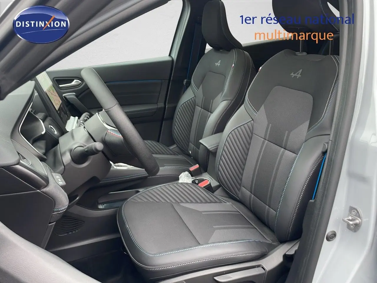 Vue intérieure côté conducteur de la Renault Symbioz 2025, sièges noirs avec surpiqûres bleues et logo Alpine brodé.