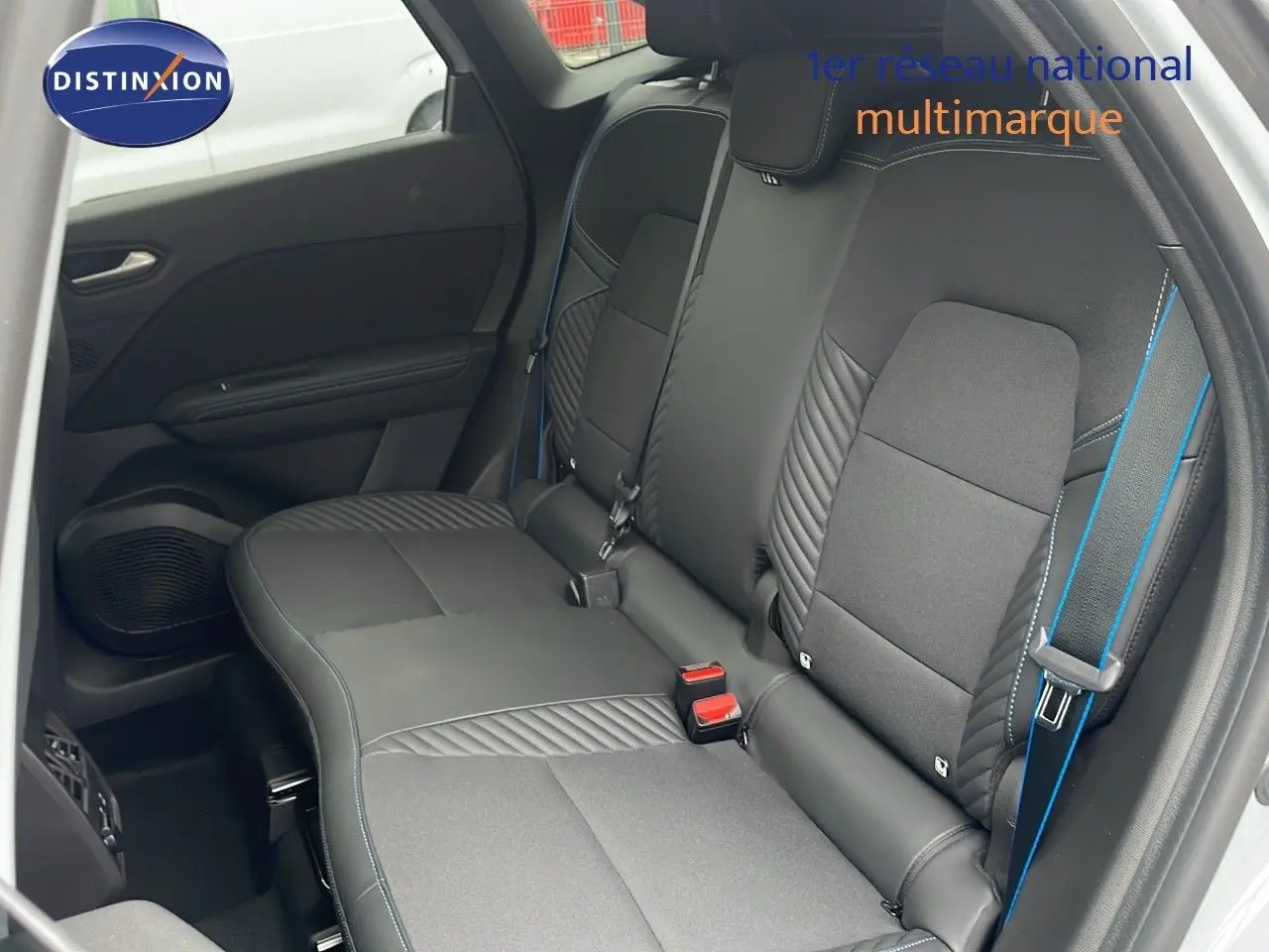 Vue intérieure côté gauche des sièges arrière noirs avec surpiqûres bleues d'une Renault Symbioz gris rafale métal 2025.