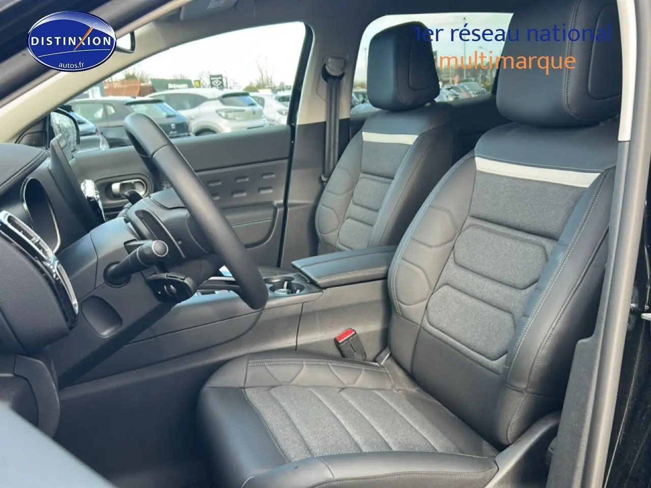 Vue intérieure côté conducteur du Citroën C5 Aircross 2025 noir, mettant en valeur les sièges cuir et tissu avec accoudoir central.