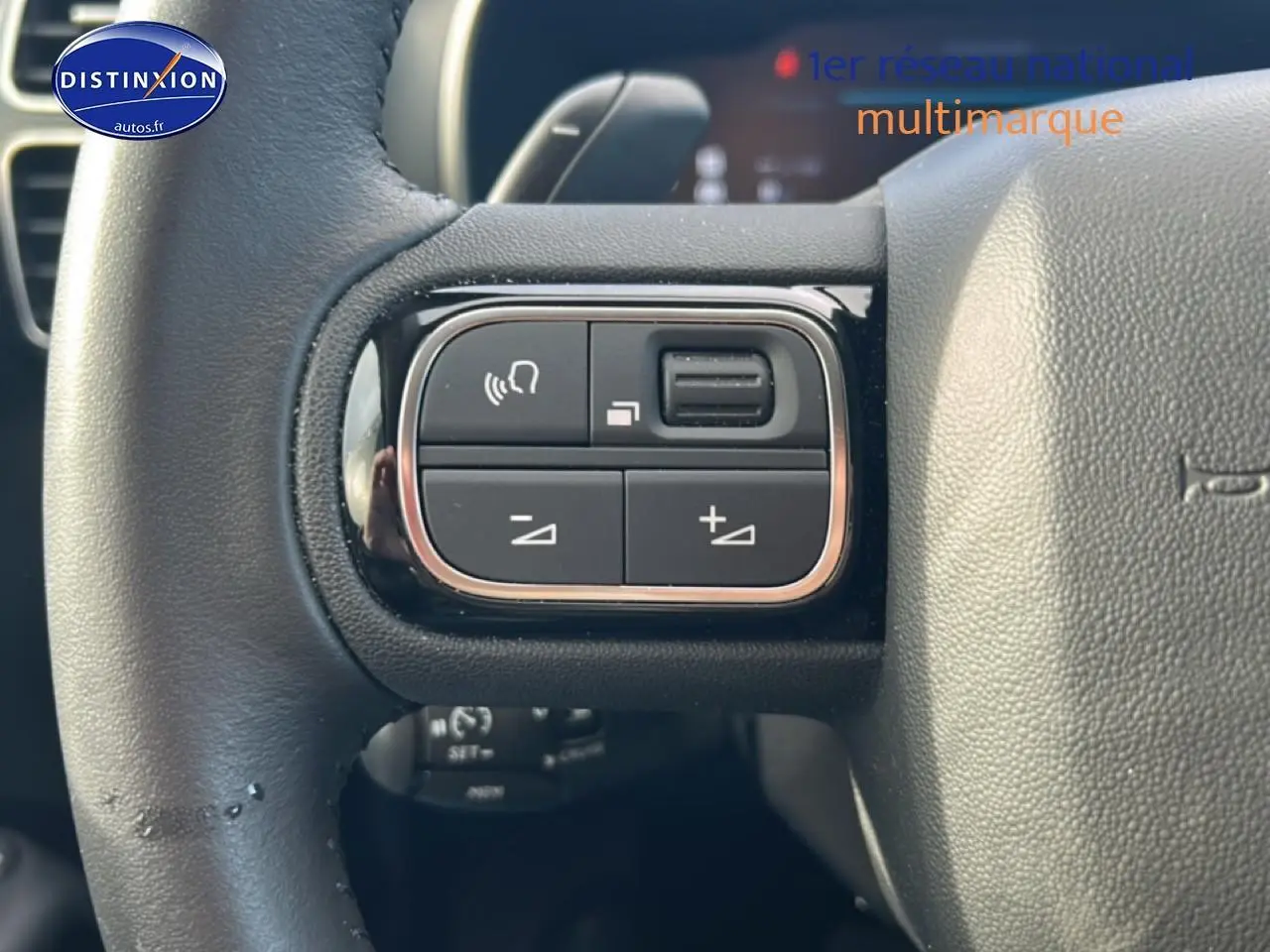 Gros plan sur les commandes gauche du volant cuir du Citroën C5 Aircross noir, version hybride 2025.