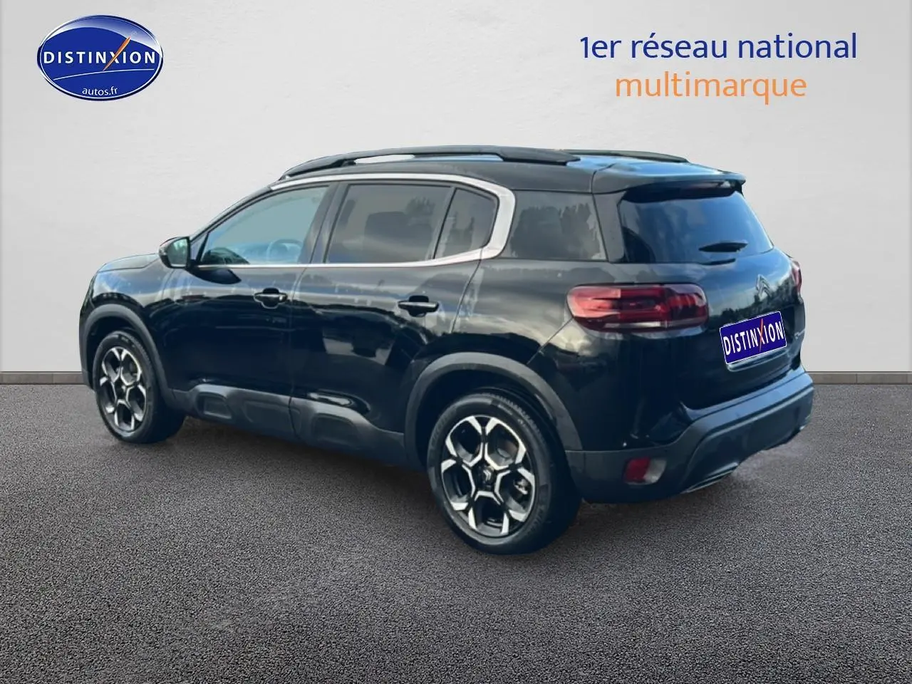 Vue 3/4 arrière droite d'un Citroën C5 Aircross noir avec barres de toit et jantes alliage distinctives.