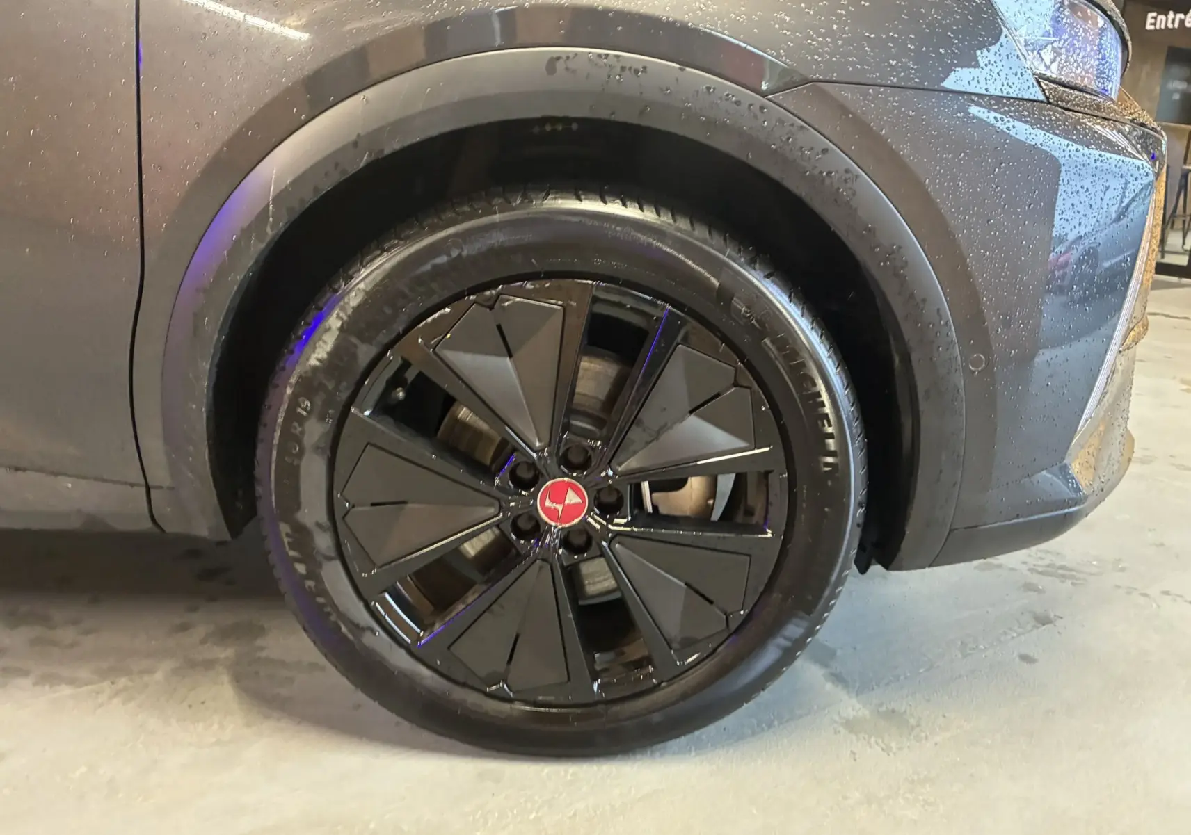 Gros plan sur la roue avant droite du DS7 E-TENSE gris 2024 avec jante noire au design géométrique et logo rouge central.